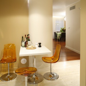 Niewielki stolik śniadaniowy wykonany z corianu (jak wszystkie blaty robocze) wraz z transparentnymi, z pomarańczowymi krzesłami (Soft Line), są efektownym elementem aranżacyjnym. Fot. Bartosz Jarosz. 
