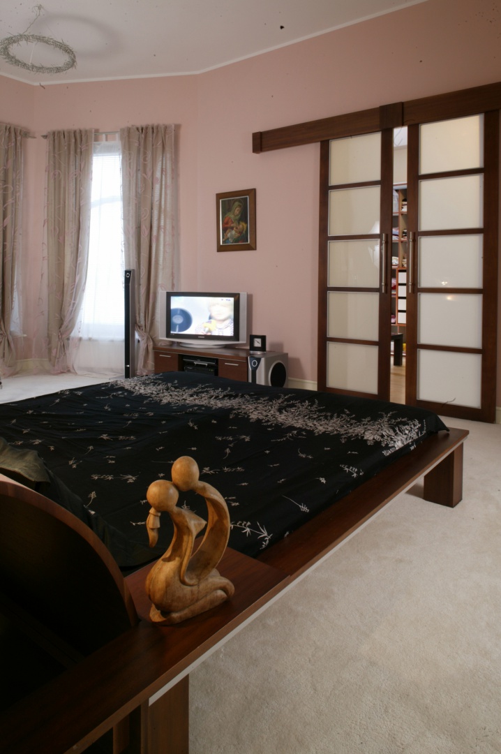 Z sypialni do garderoby prowadzą piękne, biało-brązowe drzwi, współgrające z orzechowym łóżkiem. Ich wzornictwo zostało zainspirowane Japonią.