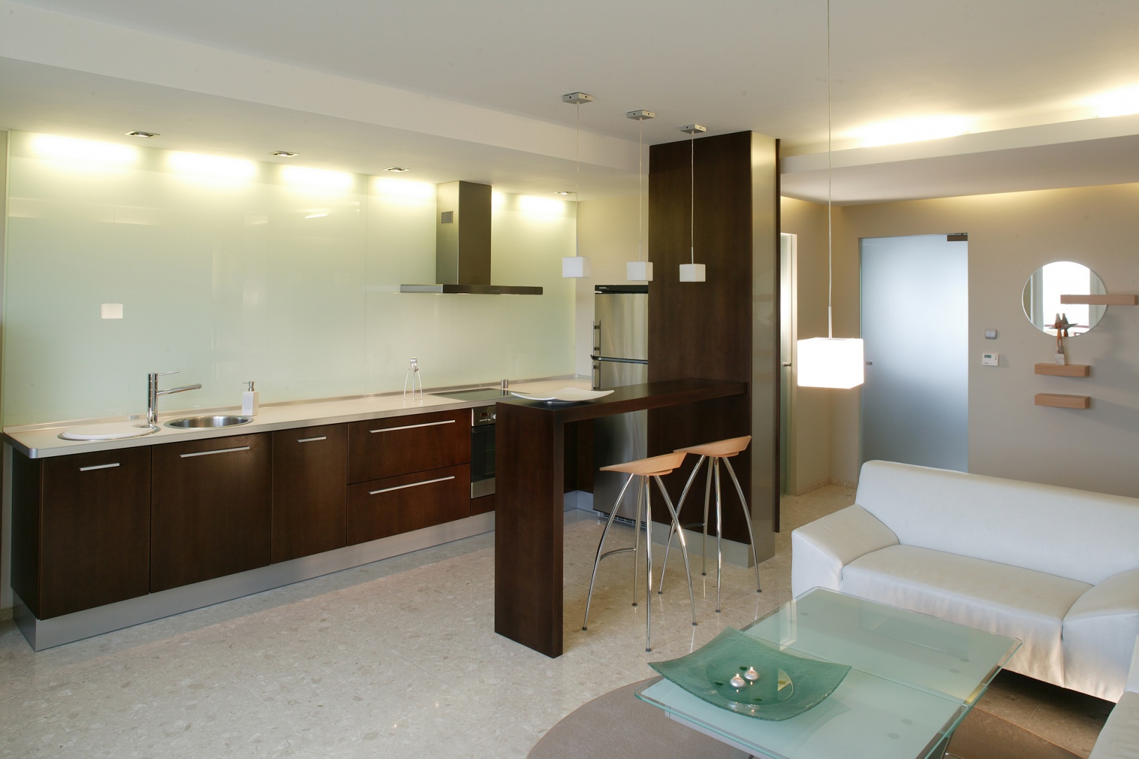 Czysta geometria zagościła w salonie. Białe kubiki wiszących lamp, ciężkie bryły skórzanego wypoczynku, prostokątne tafle szklanych drzwi. Wszystkie elementy zostały tak skomponowane, aby potęgować w pomieszczeniu wrażenie ładu i harmonii. Fot. Tomek Markowski.
