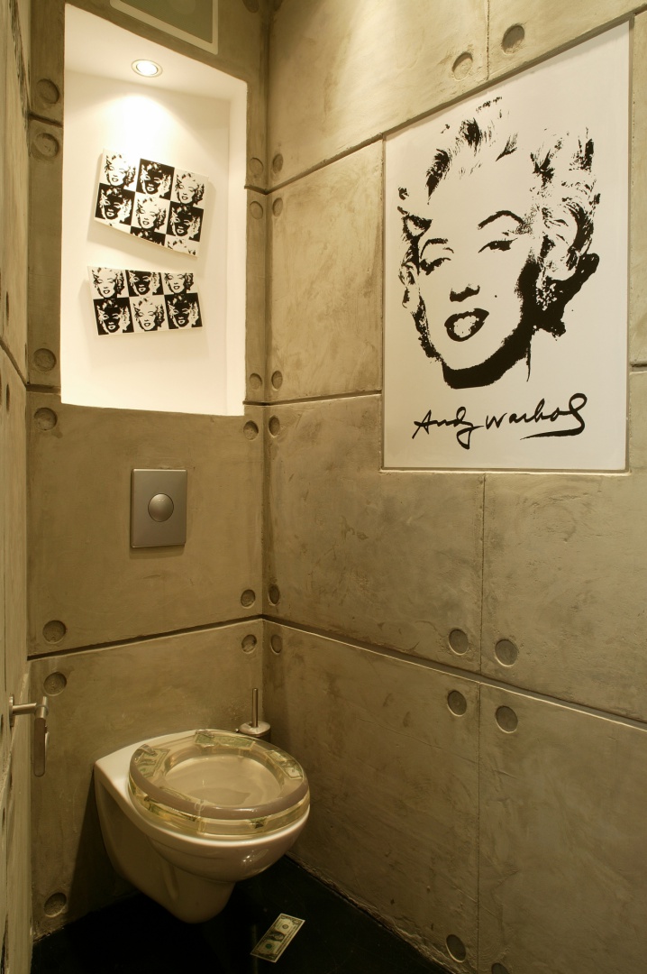 Zimne, betonowe ściany architekci zdecydowali się połączyć z pięknem Marylin Monroe, które wyraźnie kontrastuje z syntetycznie zimnym i prostym w swoim wyrazie sedesem. Fot. Marcin Łukaszewicz.