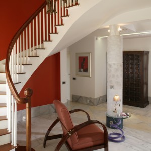 Holl jest zapowiedzią stylistyki pozostałej części domu. Biała wstęga schodów została wyeksponowana na tle „ostrej”, pomidorowej ściany. To stylistyczny skrót i zarazem wstęp do tego, na co natkniemy się dalej. Fot. Bartosz Jarosz.