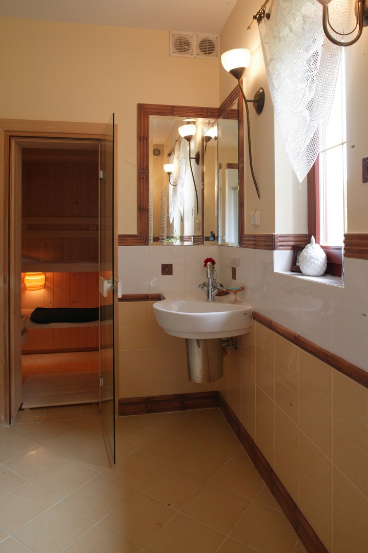 Fińska sauna ze świerku jest częścią łazienki. Narożną umywalkę wieńczy, także narożne, lustro, intrygująco powielające przestrzeń w nieskończoność.
Fot. Monika Filipiuk.