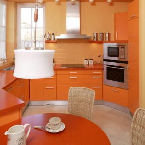 Kuchnię spowijają pomarańczowo-żółte odcienie. Formy detali - jak lampki na suficie czy dekoracja okien -  nawiązują do stylowych wnętrz rezydencji. Fot. Bartosz Jarosz.