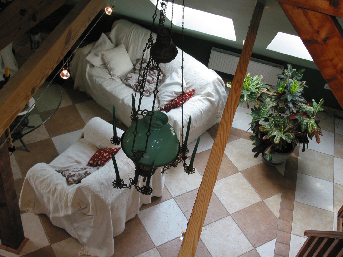 Widok na salon z antresoli. Nad wnętrzem czuwa oryginalna dziewiętnastowieczna lampa z fantazyjnymi, żeliwnymi zdobieniami i miejscami na świeczki. Obok tego właściciele postanowili umieścić zupełnie współczesne sznury halogenowych lampek. Fot. Tomek Markowski.