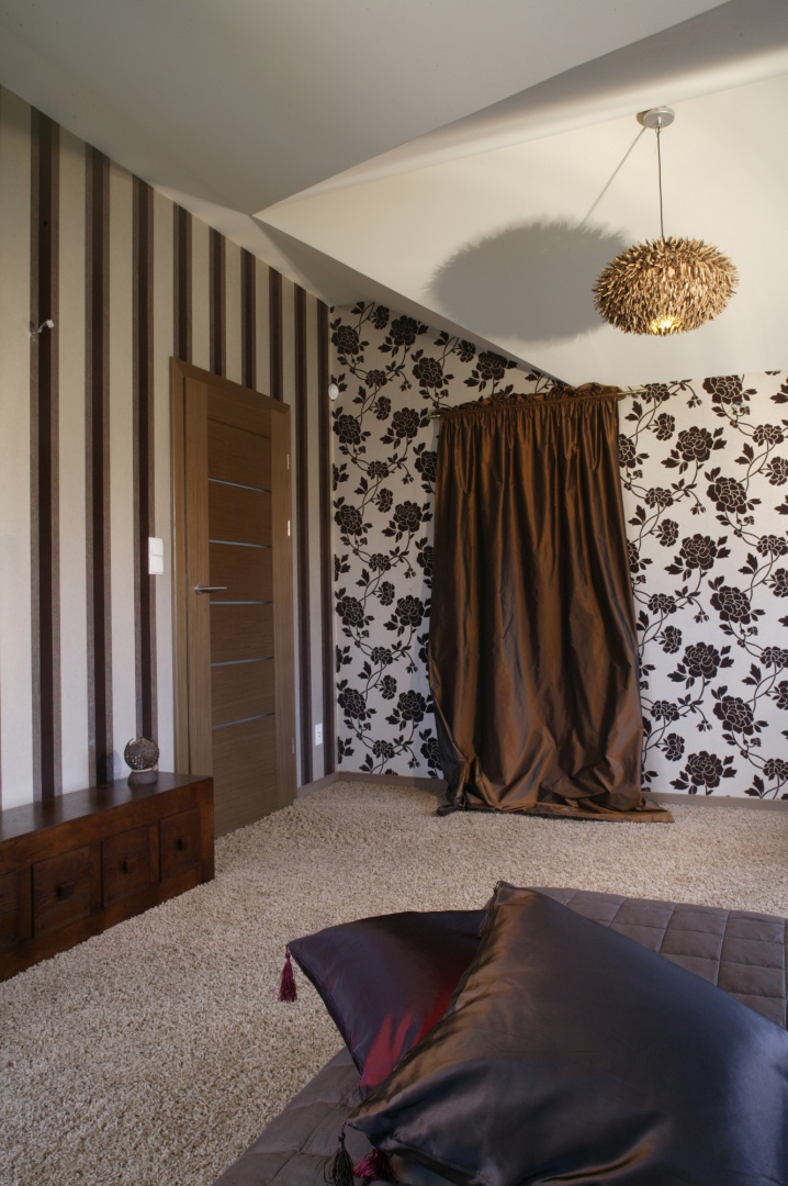 Miękka, układająca się w fałdy tafta o barwie czekolady, zastępuje drzwi do garderoby. Efektowna, jakby „włochata” lampa (Kare Design), zabawnie uzupełnia tę oryginalną aranżację. Fot. Monika Filipiuk.