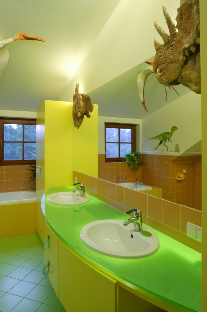 Głównym oświetleniem łazienki jest szklany blat umywalkowy, spod którego przenika mocne światło. Jego zieleń, podobnie jak posadzki, jest elementem stylizacji nawiązującym do pradawnej przyrody. Fot. Bartosz Jarosz.