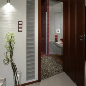 Po otwarciu drzwi od razu widać, że łazienka dzieli się na dwie kontrastujące strefy. Falista linia na podłodze, przypominająca chiński symbol Yin Yang sugeruje, że przeciwieństwa się tu wzajemnie warunkują i dopełniają.