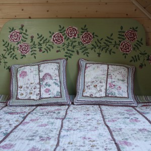 Oprócz wszechobecnego drewna i czerpanych z natury kolorów, ciepły klimat sypialni tworzą starannie dobrane naturalne tkaniny: narzuta patchworkowa, tkany ręcznie chodniczek. Fot. Bartosz Jarosz. 
