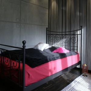 W sypialni również pojawia się „betonowa” ściana. Ociepla ją firana typu „spaghetti” i marokański dywan. Fot. Monika Filipiuk.