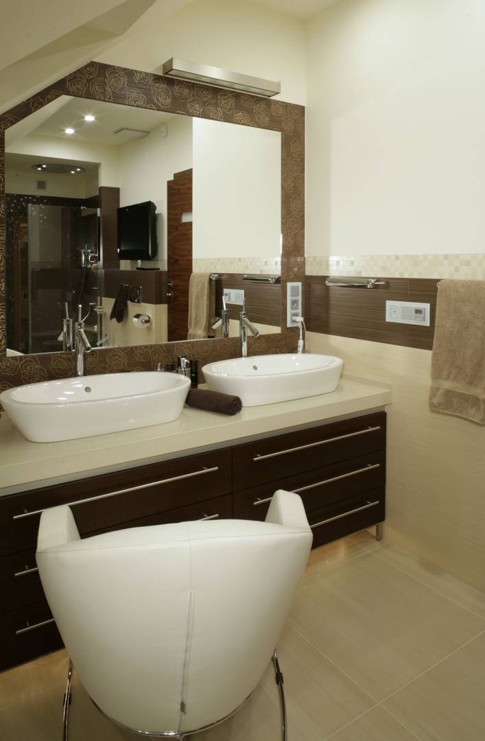Szafka pod umywalkami została wykonana z marmuru i drewna wenge. Stylowe baterie, tak jak cała łazienkowa armatura, pochodzą z oferty Hansgrohe (linia „Axor Starck”). Fot. Monika Filipiuk.