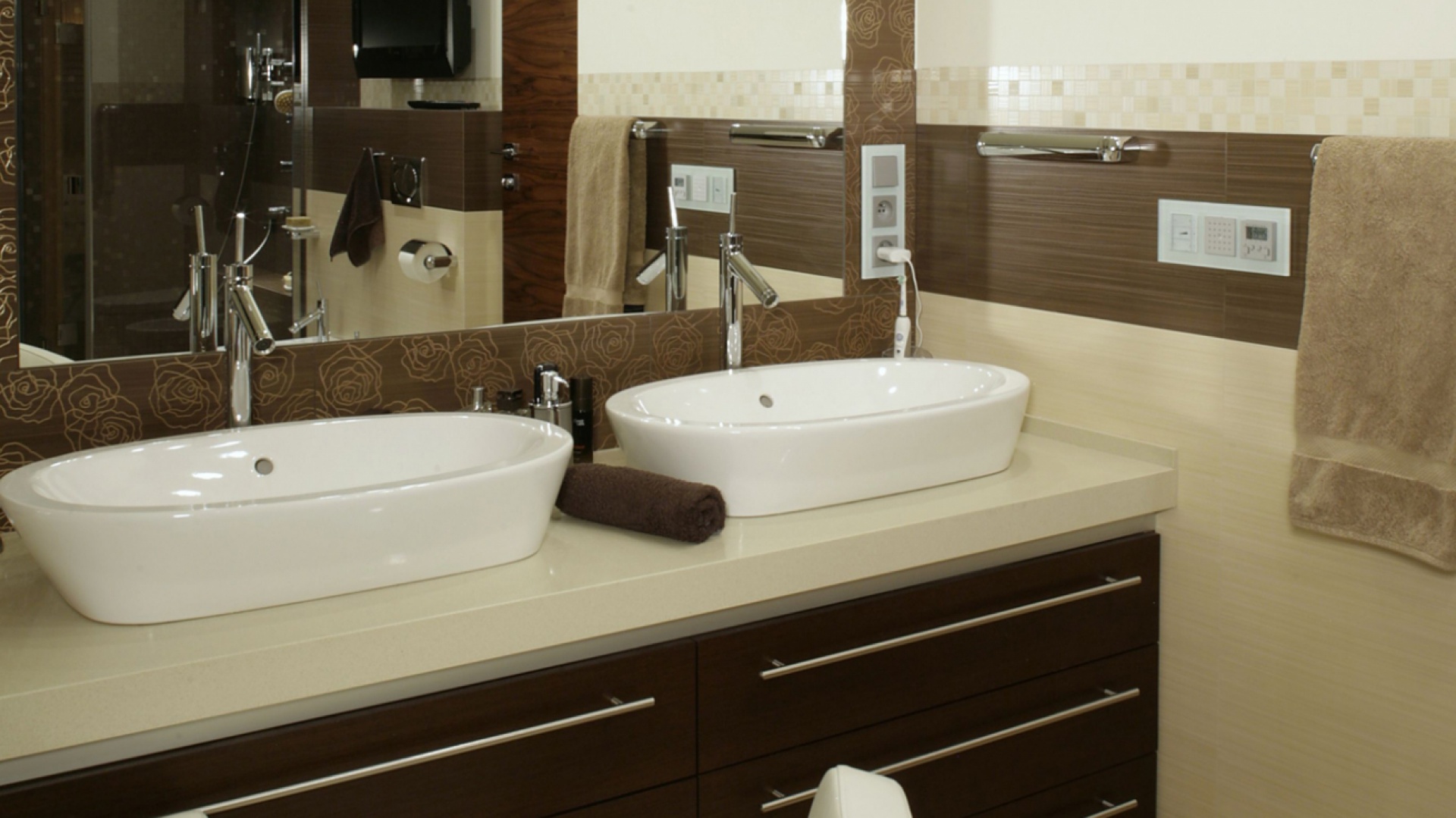 Szafka pod umywalkami została wykonana z marmuru i drewna wenge. Stylowe baterie, tak jak cała łazienkowa armatura, pochodzą z oferty Hansgrohe (linia „Axor Starck”). Fot. Monika Filipiuk.