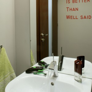 Aranżacja łazienki jest surowa, ograniczona do niezbędnych elementów. Jej „mocnym punktem” jest czerwony napis na ścianie. Fot. Monika Filipiuk.