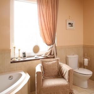 Łazienka posiada zarówno wannę, jak i prysznic. Po relaksującej kąpieli można chwilę wypocząć w wygodnym fotelu pokrytym tym samym materiałem, z jakiego zostały wykonane zasłony. Fot. Bartosz Jarosz.