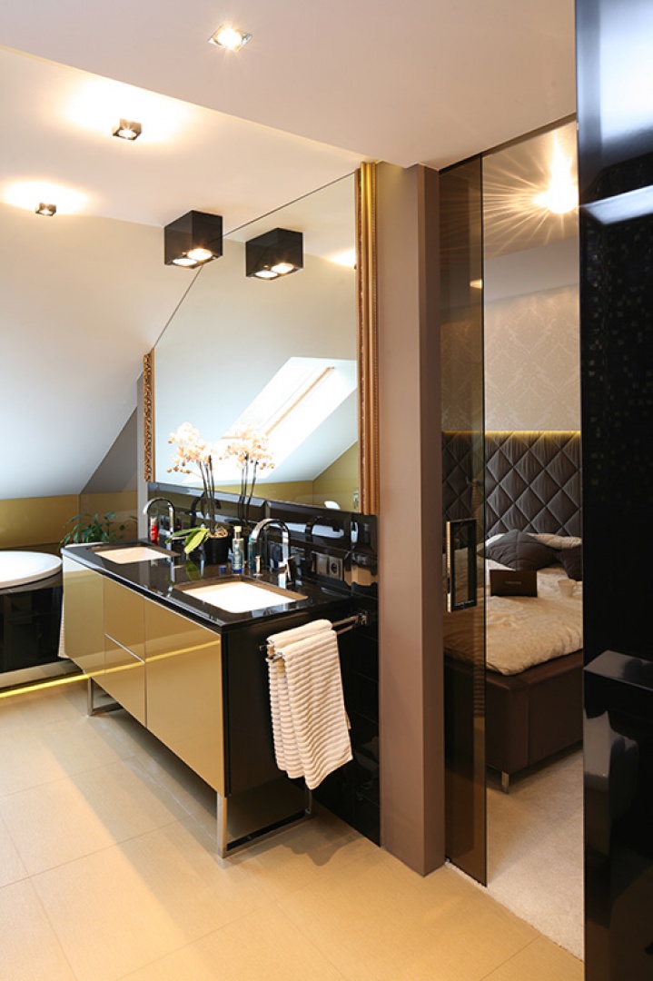 Elegancji i szyku nadaje gustowna kompozycja materiałów. Fronty szafki ze szkła „Lacobel Gold”, blat z granitu „Belfast”, umywalki
„Loop&Friends” Villeroy&Boch, baterie Graff „Sade”. Efekt pikowania na zagłówku, widocznym w tle, powtarza okładzina z płytek „London
Piccadilly Black by Maciej Zień” Tubądzin. Fot. Bartosz Jarosz.
