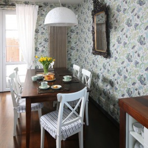 Do masywnego drewnianego stołu, będąca miejscem wspólnych rodzinnych posiłków, dobrano lżejsze w formie krzesła w białym kolorze. Fot. Bartosz Jarosz.
