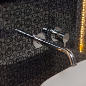 Ścianę nad umywalką w łazience pokryto pięknymi srebrno-czarnymi płytkami z delikatnym, eleganckim wzorem. Fot. Decoroom.