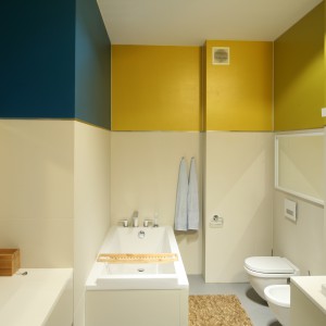 Nie tylko lustra, których w tej łazience jest aż trzy ale także  kolorowy fragmenty ścian, których pas wyraźnie odcina się od całości powodują, że łazienka wydaje się większa i wyższa. Projekt: Konrad Grodziński. Fot. Bartosz Jarosz.
