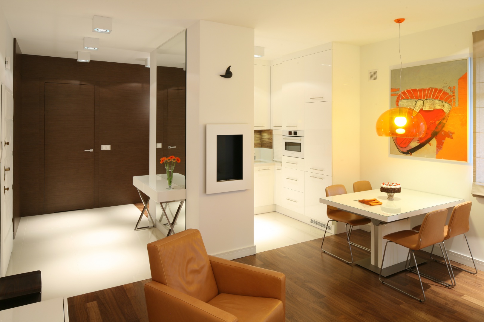 Strefa wejścia w eleganckim apartamencie urządzono została w bieli, którą ociepla drewno w ciepłym wybarwieniu. Projekt: Małgorzata Galewska. Fot. Bartosz Jarosz.