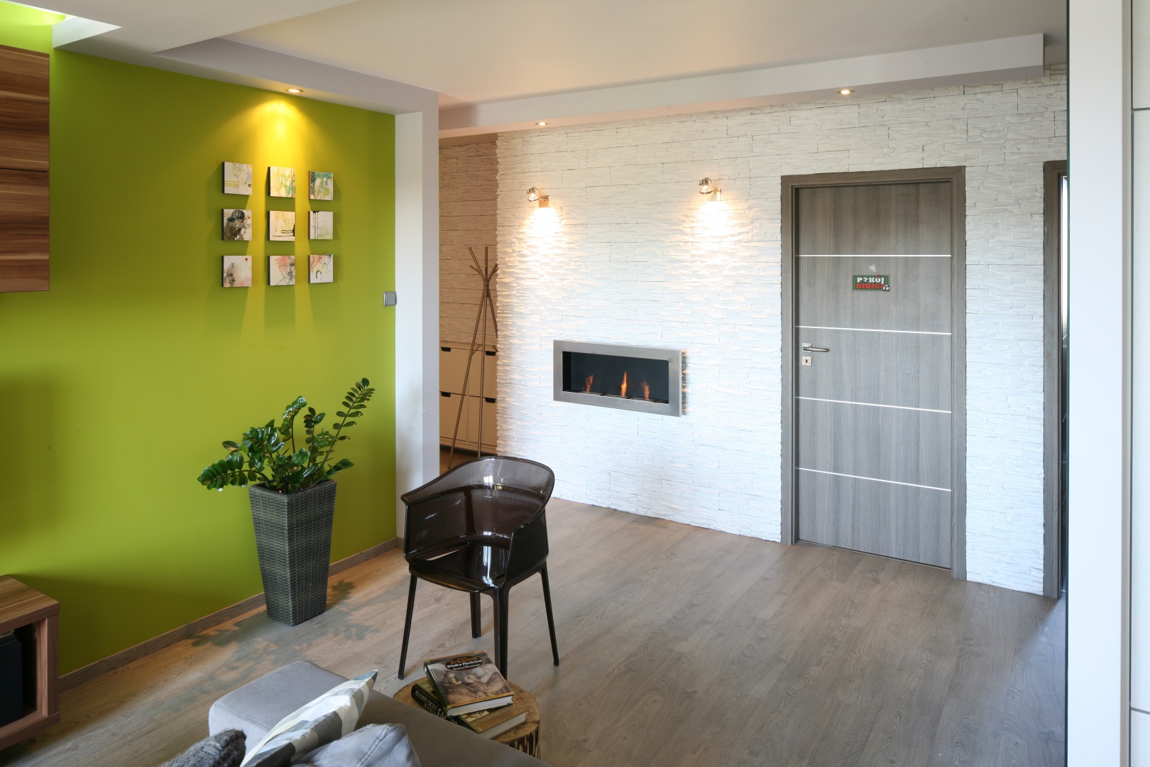 W niewielkim mieszkaniu strefa wejścia przybrała salonowy charakter. Świadczy o tym udekorowana kamieniem ściana oraz elegancki biokominek. Projekt: Arkadiusz Grzędzicki. Fot. Bartosz Jarosz.