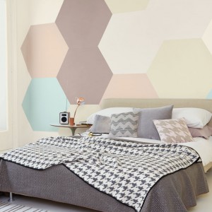 Pastelowe sześciokąty: delikatne beże, brązy, szarości i błękity tworzą na ścianie za łóżkiem oryginalną dekorację. Fot. Dulux.