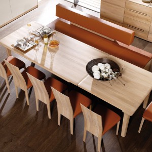 Pomarańczowa tapicerka krzeseł i nowoczesnej ławy sprawia, że jadalnia staje się jeszcze cieplejsza i zyskuje apetyczny wygląd. Fot. Voglauer.