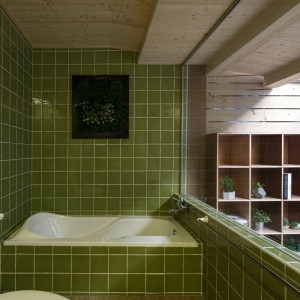 Łazienkę z widokiem na taras wykończono w kolorze zgniłej zieleni. Naturalna barwa koresponduje z materiałem użytym na suficie pomieszczenia oraz z widokiem za przeszkleniem. Projekt: HAO Design Studio. Fot. Joey Liu.