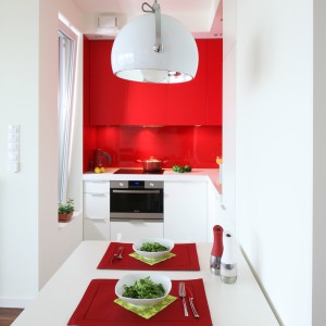 Dzięki czerwonym szafkom niewielka kuchnia ma wyrazisty wygląd, przez co staje się bardziej widoczna na mapie mieszkania. Projekt: Iza Szewc. Fot. Bartosz Jarosz.