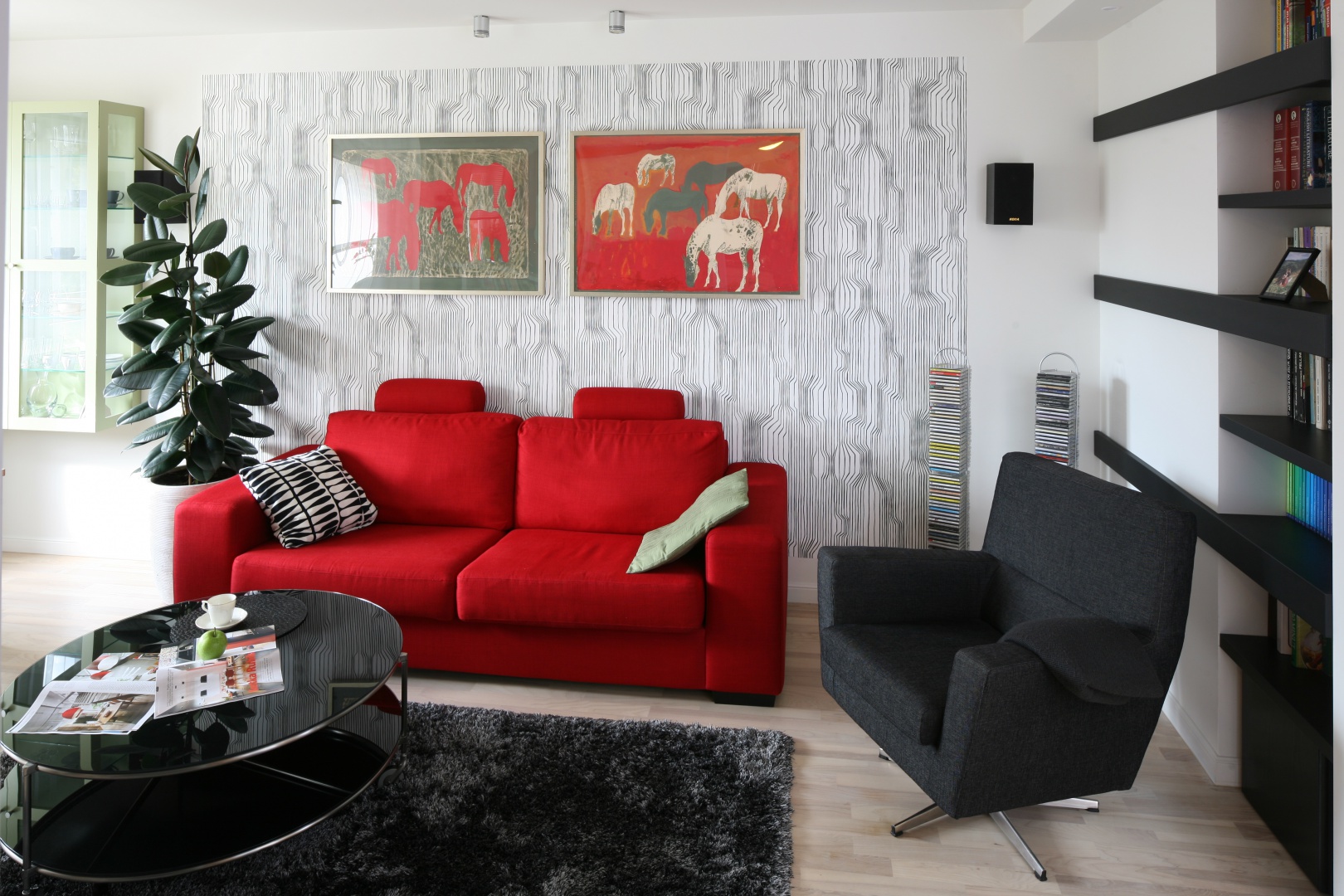 W nowoczesnym salonie biel i czerń tworzą subtelne tło dla intensywnej czerwieni, która emanuje z ekspresyjnych obrazów na całe wnętrze. Projekt: Marta Kruk. Fot. Bartosz Jarosz.