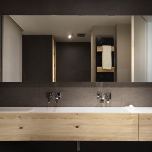 Ściany w łazience pokrywa wyrazista czerń, która pięknie kontrastuje z jasnym drewnianym dekorem. Całość zamknięto w kubistyczne formy. Projekt: Coblonal Arquitectura. Fot. Sara Riera.
