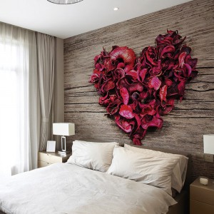 Serce usypane z płatków róż na tle drewnianej tekstury wprowadza do sypialni romantyczną atmosferę. Fot. Dekornik.