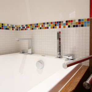 Łazienka stworzona dla całej rodziny dzięki bieli, wydaje się niezwykle przestronna. Kolorowa mozaika ożywia aranżację. Projekt: Dorota Szafrańska. Fot. Bartosz Jarosz.