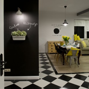 Ścianę przy wejściu do salonu pomalowano czarną farbą tablicową, która kolorystycznie idealnie harmonizuje z szachownicą na podłodze. Projekt: SHOKO.design. Fot. Małgorzata Opala.
