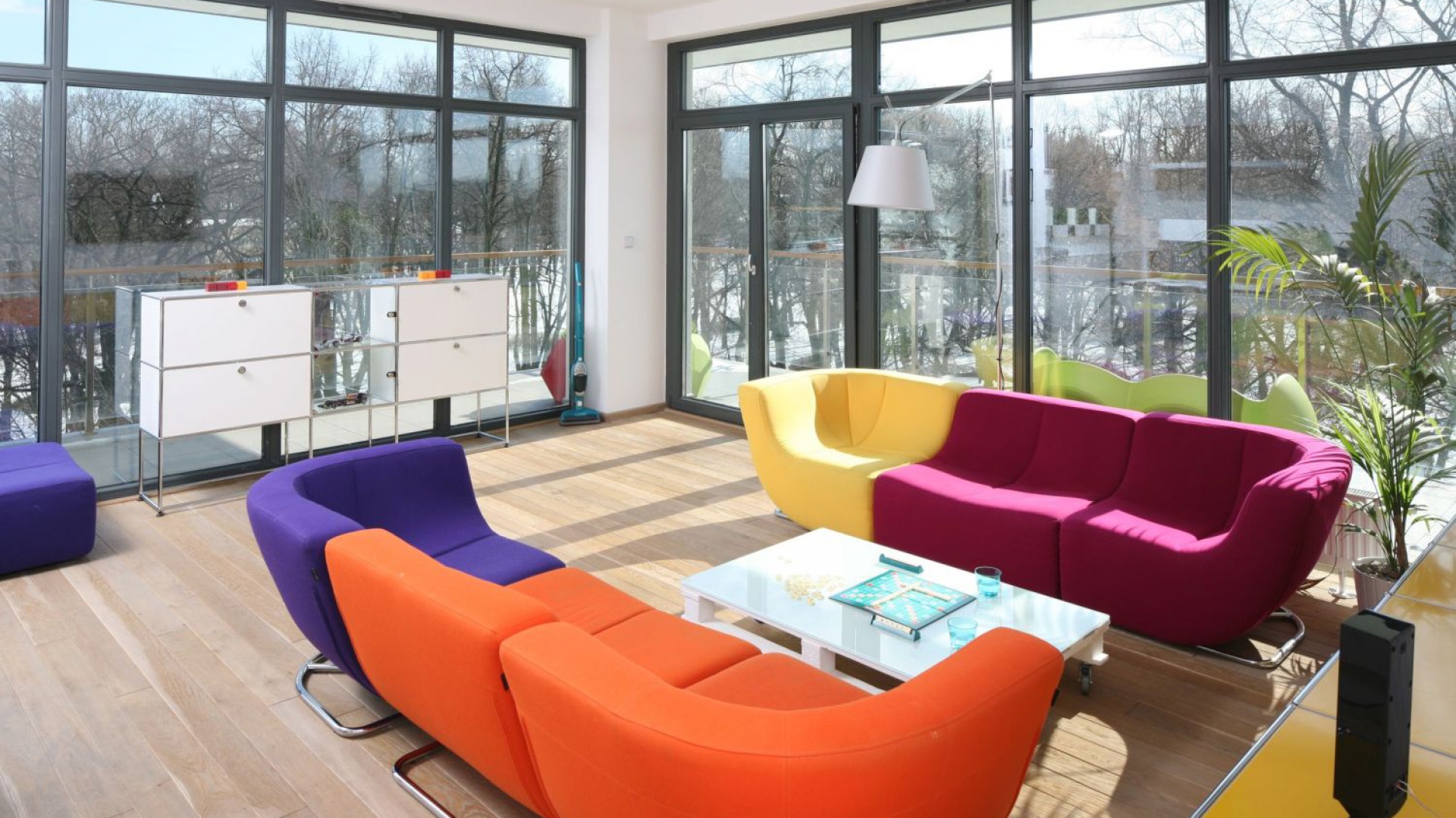 Przestronny salon, całkowicie przeszklony zdobi pokaźnych rozmiarów multikolorowa sofa. Tu wygodnie można podziwiać widoki za okien. Projekt: Konrad Grodziński. Fot. Bartosz Jarosz.