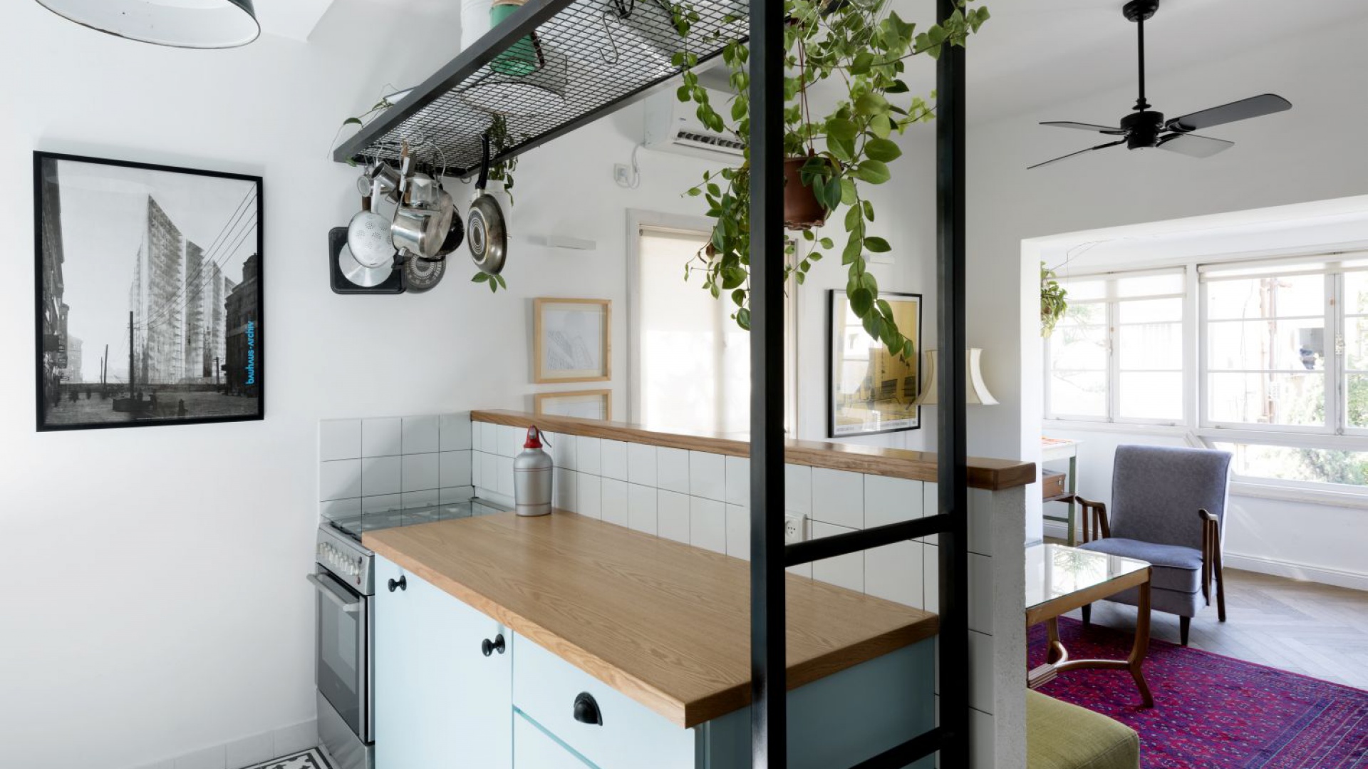 Czarna półka pełni między innymi funkcję kwietnika. Kolorystycznie idealnie harmonizuje z uchwytami mebli kuchennych i loftową lampą. Projekt: Studio Raanan Stern. Fot. Gidon Levin.
