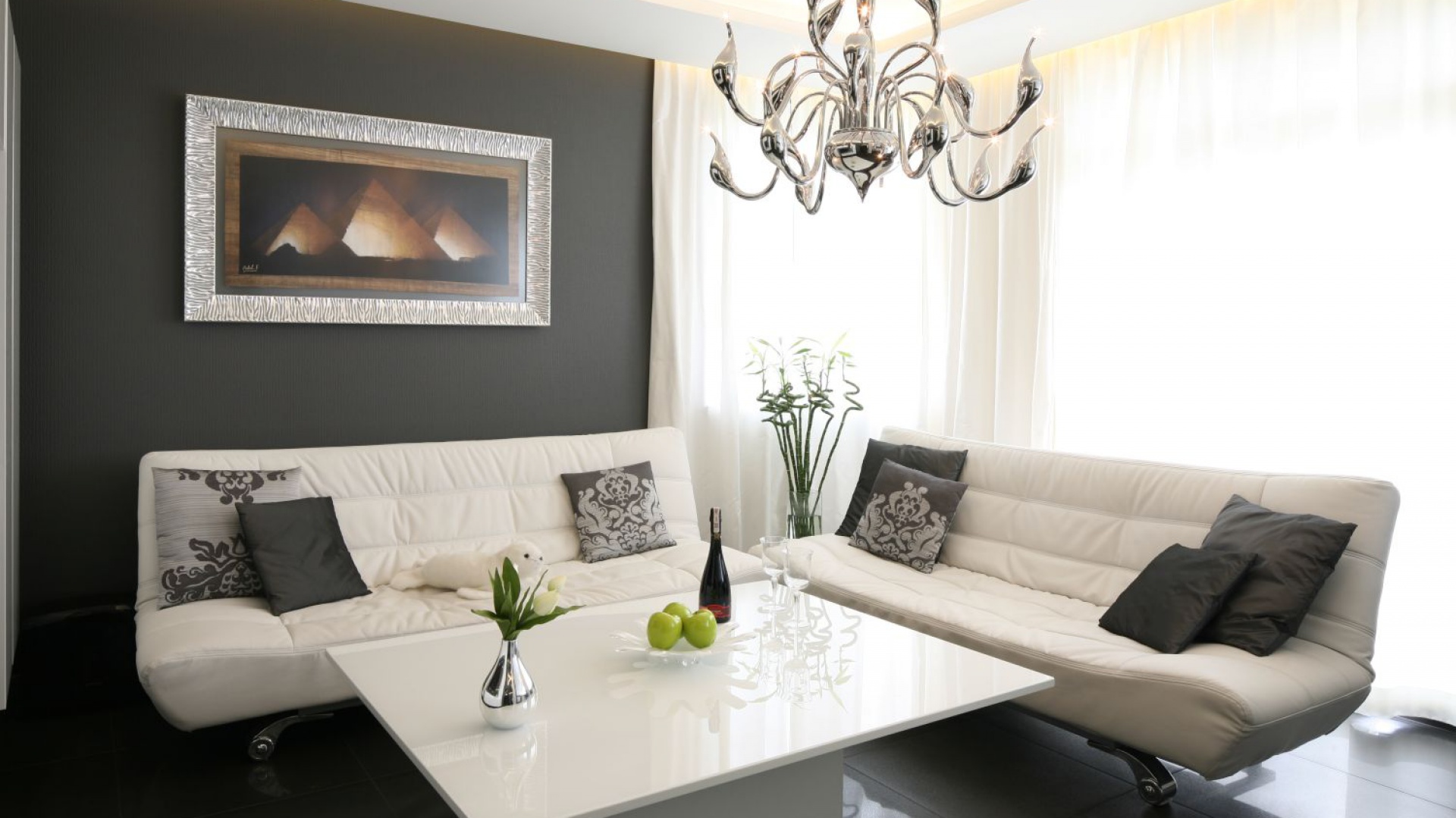 Elegancki salon urządzono w czerni i bieli. Białe sofy na lekki nóżkach uzupełnia stolik z lakierowanym na wysoki połysk obszernym blatem. Projekt: Łukasz Sałek. Fot. Bartosz Jarosz.