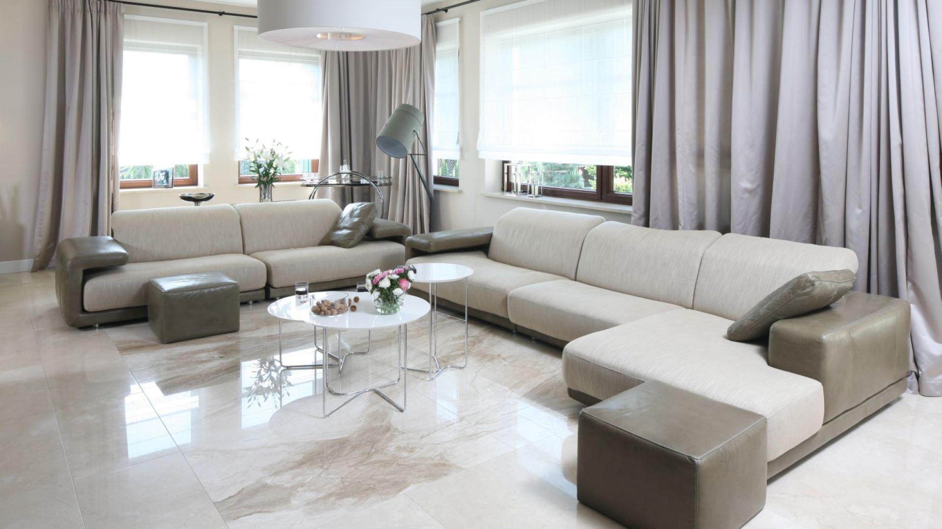 Elegancki salon zdominowały jasne barwy obecne zarówno w kolorystyce ścian i podłóg, jak i wyposażenia: eleganckich kanap, stylowy zasłon oraz nowoczesnych stolików czy lamp. Projekt: Katarzyna Koszałka. Fot. Bartosz Jarosz.
