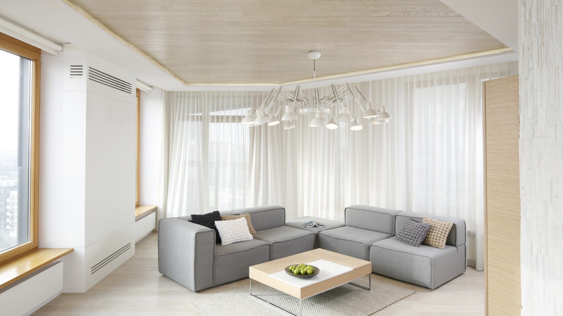 Elegancki salon urządzono w bieli i szarości. Ograniczone do minimum wyposażenie podkreśla jego minimalistyczny styl. Całość ociepla drewno. Projekt: Maciej Brzostek. Fot. Bartosz Jarosz.