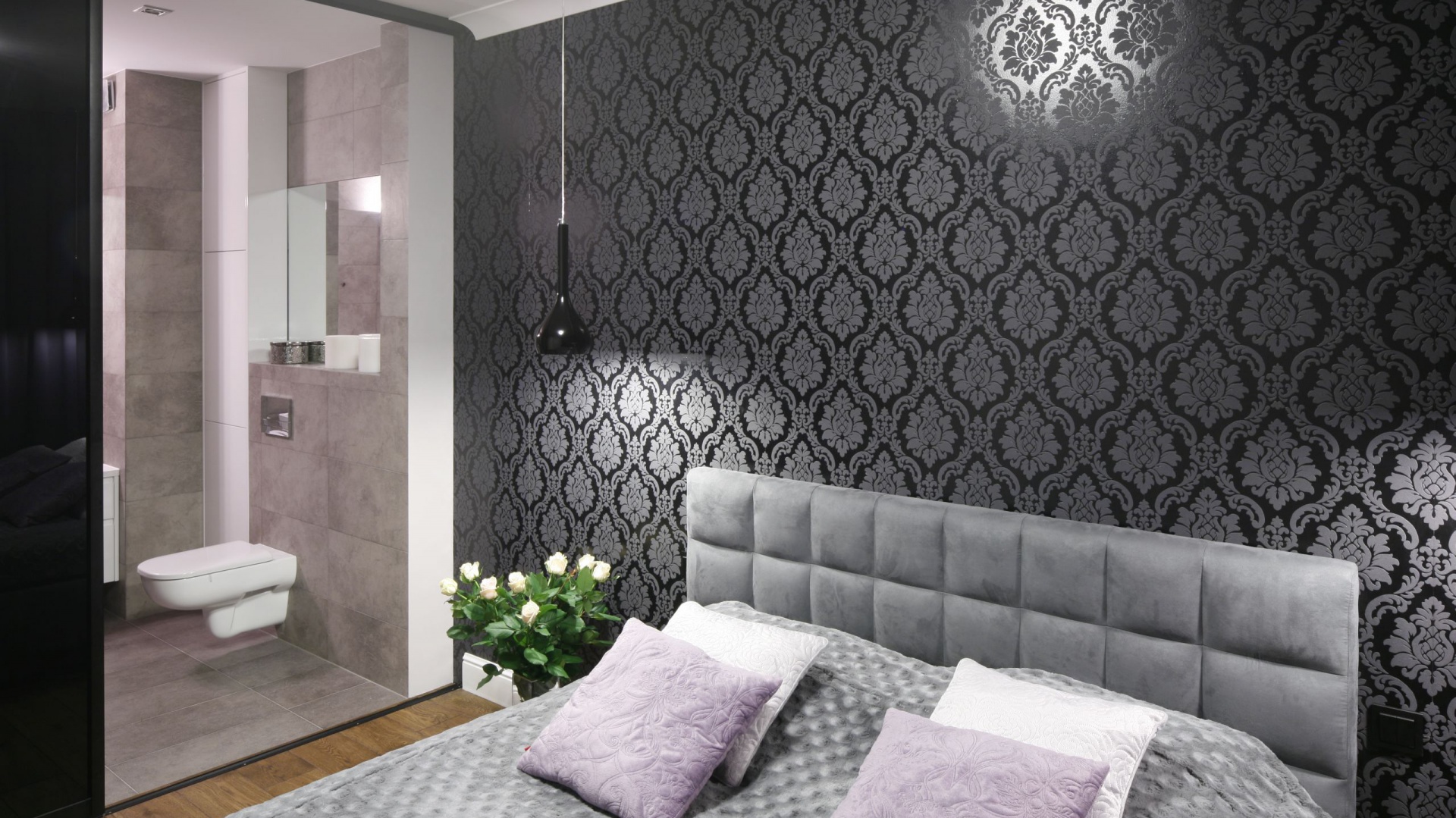 Elegancka i przytulna sypialnia z piękna tapetą za łóżkiem to prywatny azyl pani i pana domu: prosto z sypialni można wejść do łazienki urządznej w stylistyce loft. Projekt: Karolina Łuczyńska. Fot. Bartosz Jarosz
