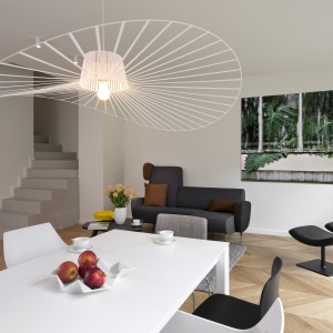 Obok mebli, imponującą dekoracją jest również oświetlenie. Designerska lampa nad stołem jadalnianym rozpościera swój ażurowy abażur, górując nad wnętrzem i przyciągając wzrok. Fot. Nickel Development