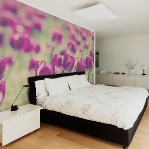 Kwitnąca łąka rozpościera się na całej ścianie za łóżkiem w sypialni Fot. Big-trix