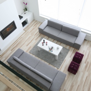 Dwie eleganckie szare kanapy organizują przestrzeń salonu o imponującej wysokości. Projekt: Karolina i Artur Urban. Fot. Bartosz Jarosz