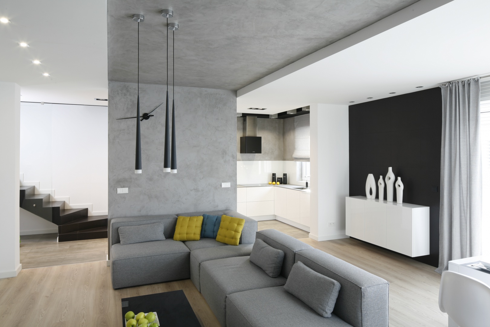 Nowoczesny minimalistyczny salon urządzono tak, aby najmocniejszym dekoracyjnym aspektem stał się sam kącik wypoczynkowy. Wyznacza go pas betonowej szarości idący od ścianki działowej przez sufit. Projekt: Karolina Stanek-Szadujko, Łukasz Szadujko. Fot. Bartosz Jarosz
