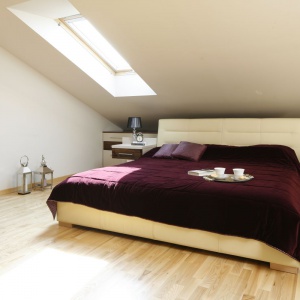 Urządzona na poddaszu sypialnia zyskuje wrażenie większej przestrzeni za sprawą jasnych ścian i jasnego drewna na podłodze. Projekt: Jolanta Kwilman. Fot. Bartosz Jarosz