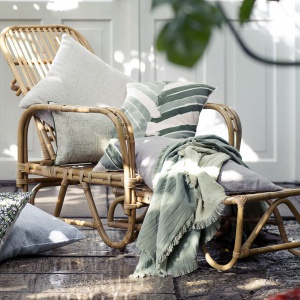 Komplet tekstyliów dekoracyjnych idealny zarówno do wnętrz, jak i na taras lub balkon. Utrzymany w kolorach zieleni i szarości. Fot. Broste Copenhagen