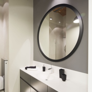 W łazience nad szafką z umywalką zawisło okrągłe, nowoczesne lustro. Projekt: Szymon Chudy. Fot. Bartosz Jarosz