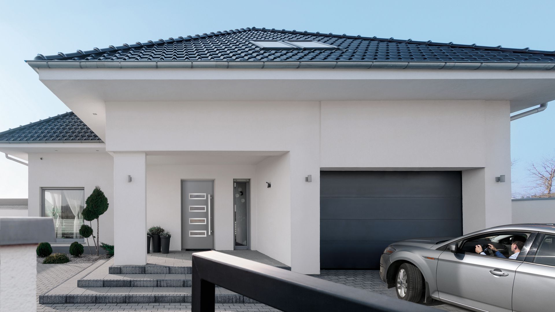 Brama UniTherm powstała w odpowiedzi na potrzeby budownictwa energooszczędnego. W pełni wykorzystuje właściwości cieplne panelu Innovo o grubości 60 mm oraz zastosowanych w niej systemów uszczelnień. To więcej zaoszczędzonej energii w domu, ponieważ straty ciepła zostały wyeliminowane w najbardziej newralgicznych miejscach skrzydła bramy. Dostępna w ofercie firmy Wiśniowiski. Fot. Wiśniowski