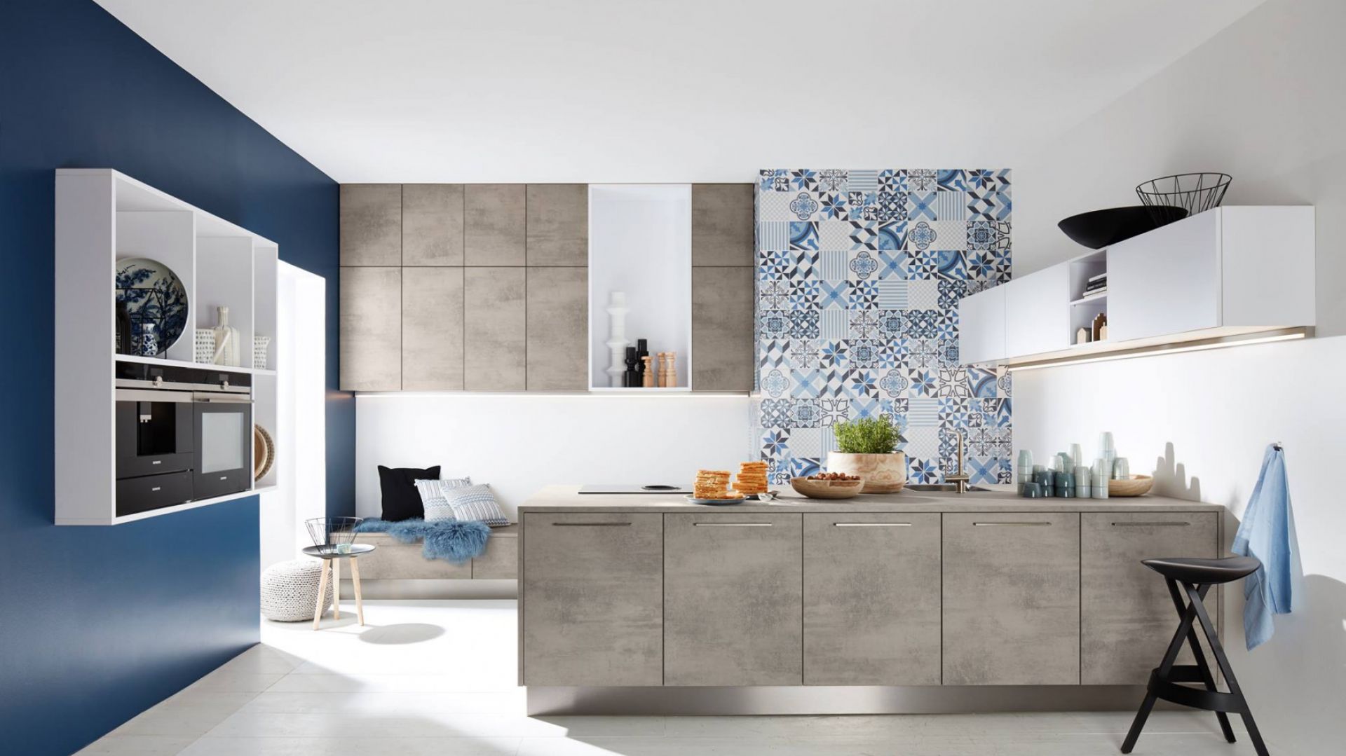 Szare fronty szafek półwyspu kuchennego nawiązują do modnej stylistyki imitującej beton. Idealnie współgrają z majoliką na ścianie. Fot. Nolte Kuchen
