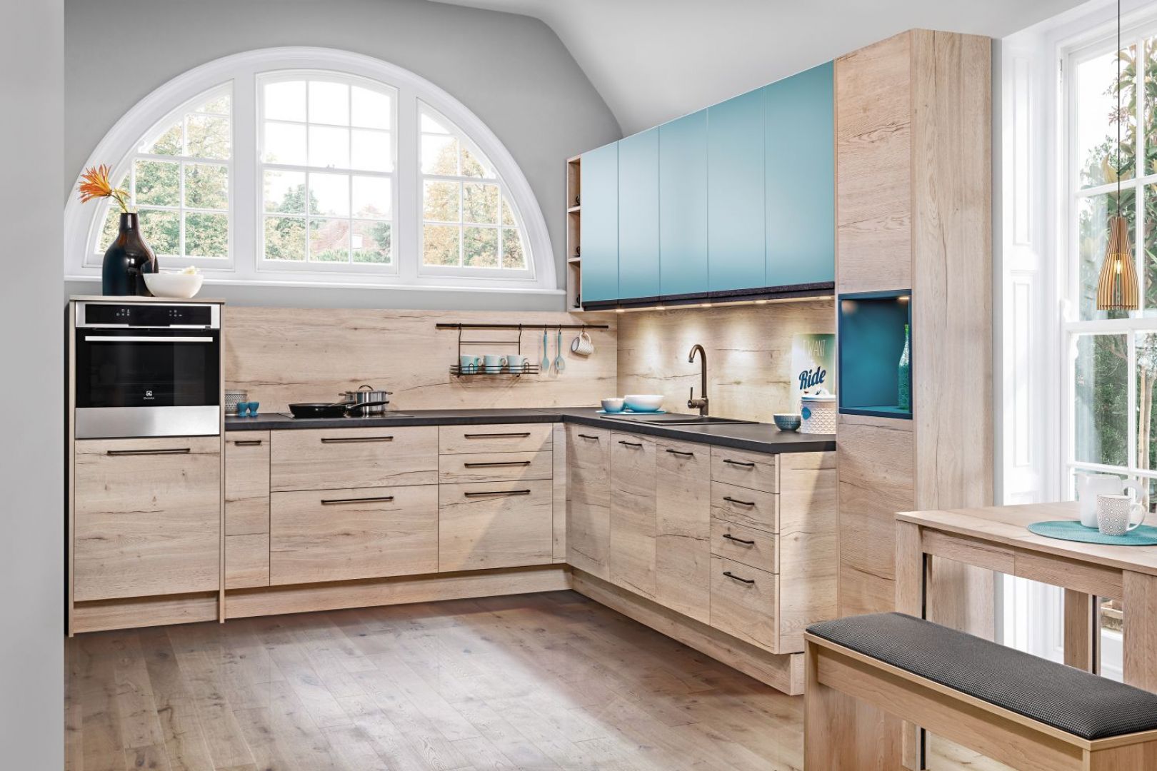 Zabudowę kuchenną z przewagą dekorów drewna można ożywić intensywnym akcentem kolorystycznym, ciekawie wkomponowanej  w bryłę mebli z systemu KAMplus. Fot. KAM 