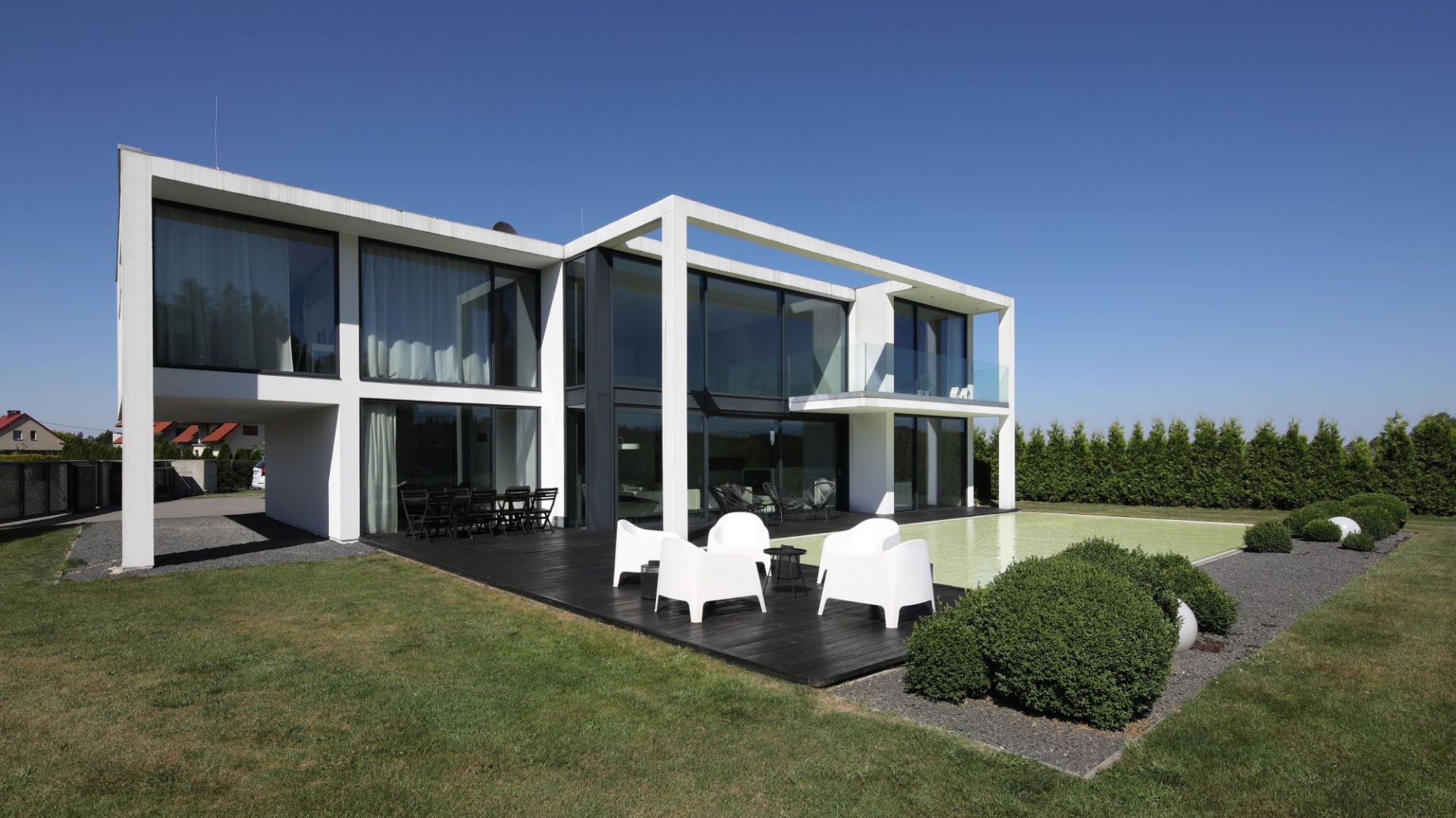 Beton House to dwupiętrowa bryła o prostej formie i białej kolorystyce. Od strony ogrodu dominują tu duże, dwukondygnacyjne przeszklenia. Projekt: arch. Hanna i Seweryn Nogalscy, Beton House Architekci. Fot. Bartosz Jarosz