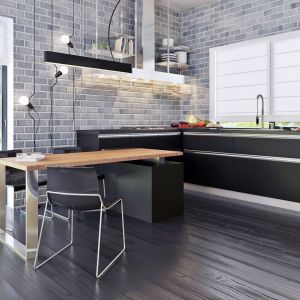 W prostej, minimalistycznej kuchni zachowano kolorystykę zastosowaną w całej części dziennej domu. Czarne fronty połączono z elementami ze stali szlachetnej oraz ocieplono drewnianym blatem. Projekt Zx63, Zespół Z500.